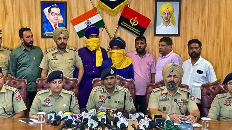 Two Nihang Sikhs in traditional attire being escorted by Punjab Police officers following their arrest.